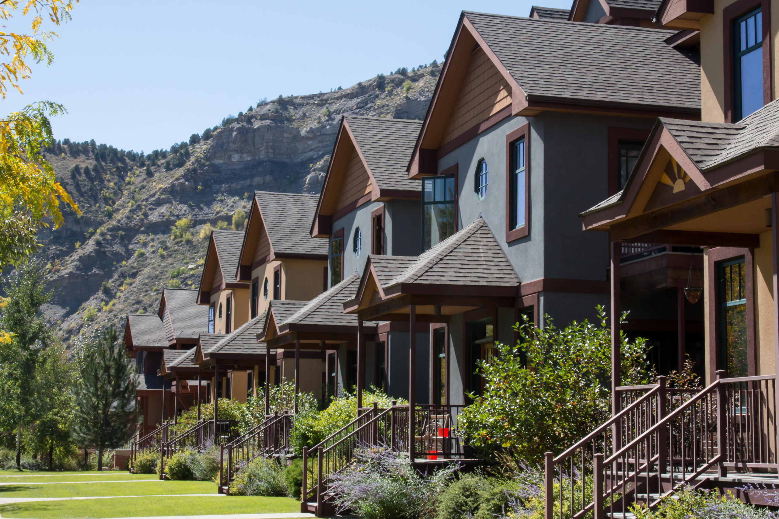 A row of townhomes is shown in front of a mountainous backdrop.